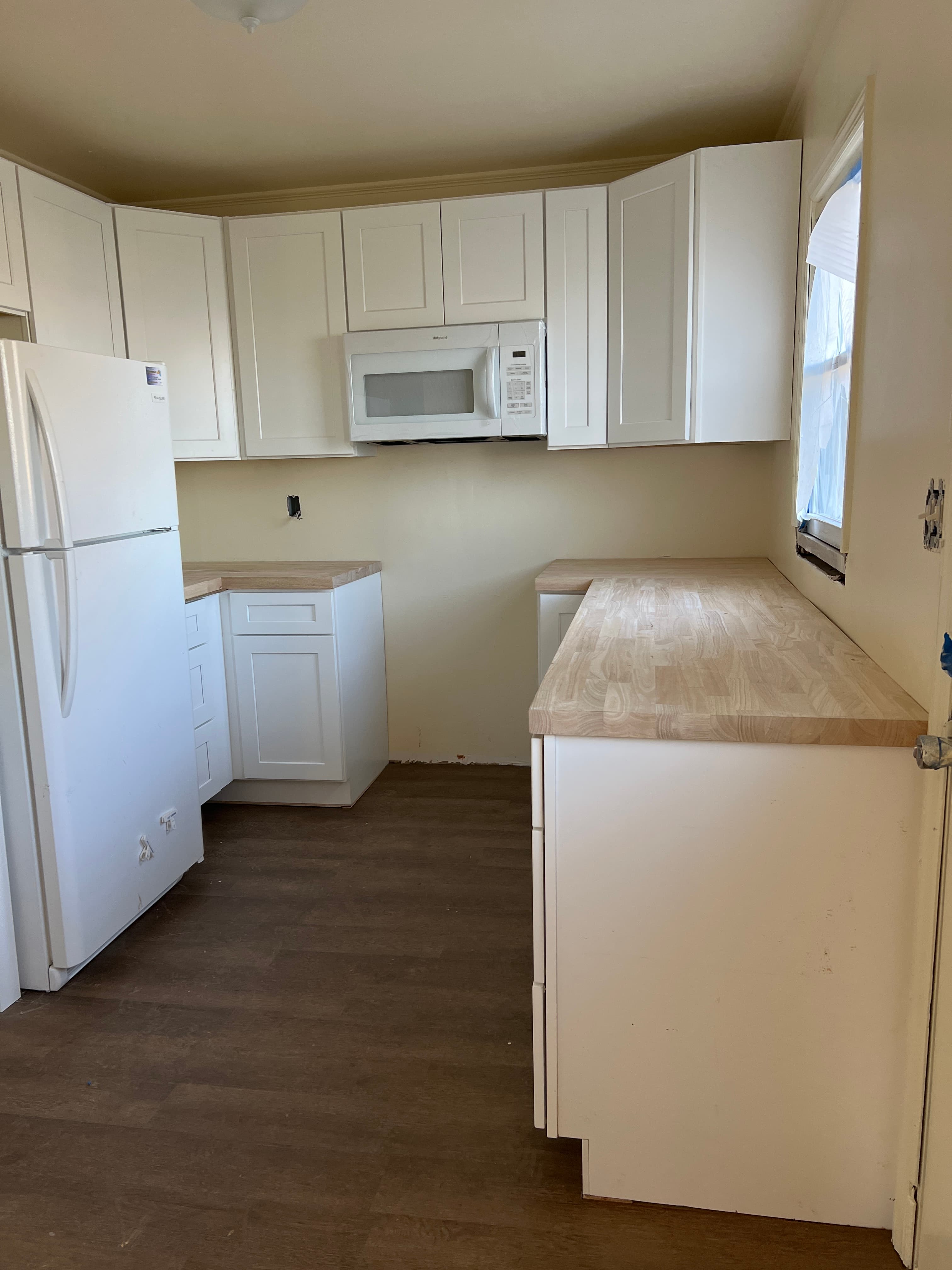 Compact white kitchen with Shaker cabinets and butcher block counters