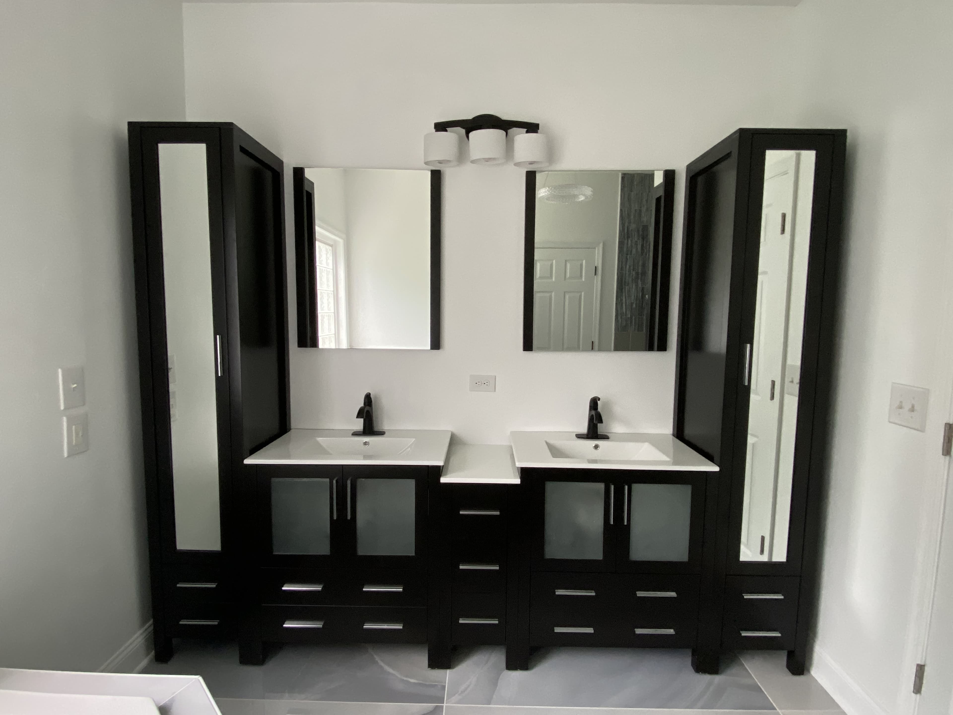 Luxury double vanity bathroom with black cabinets and modern mirrors