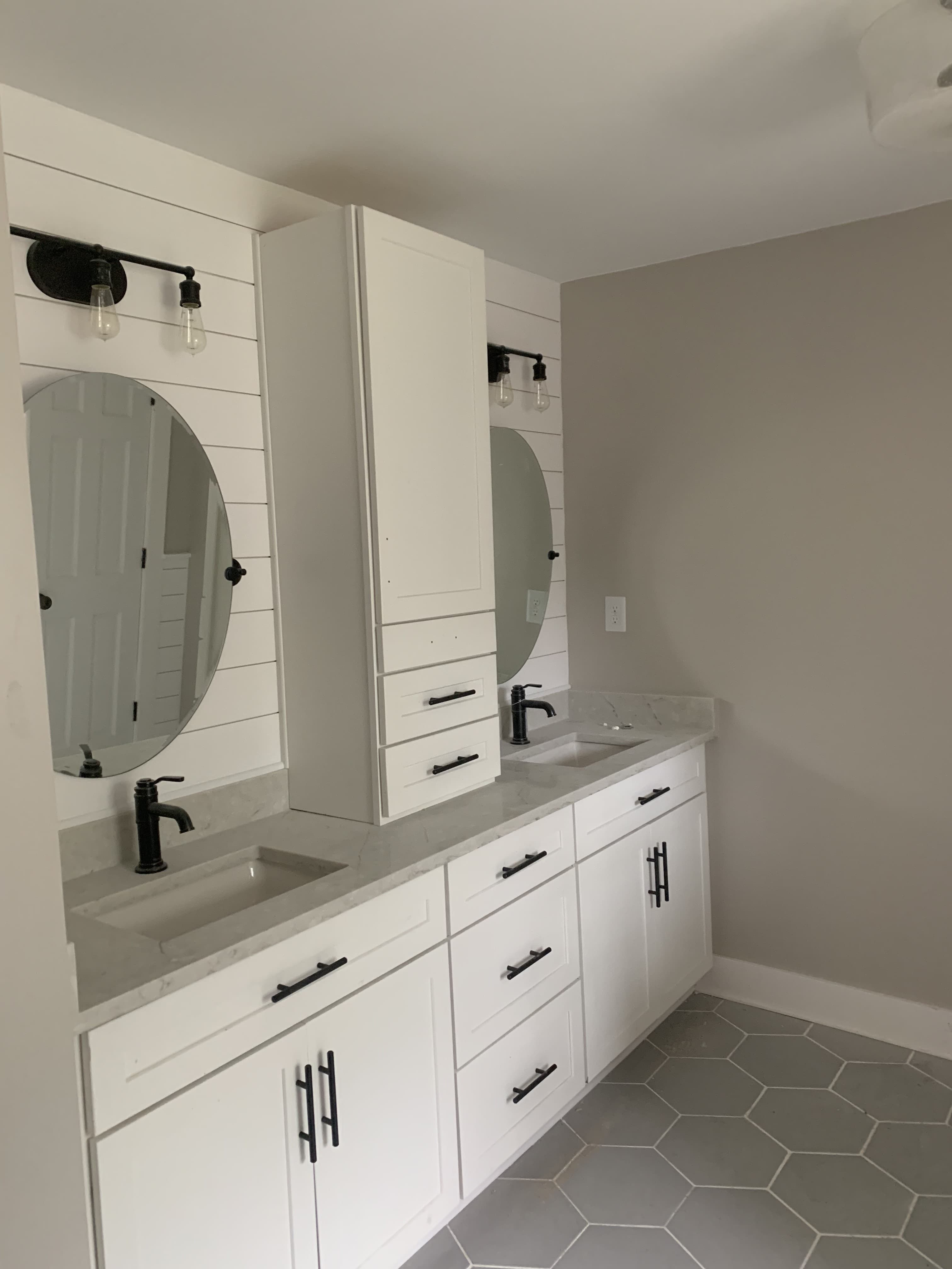 Farmhouse double vanity bathroom with white cabinets and hexagonal tile floor