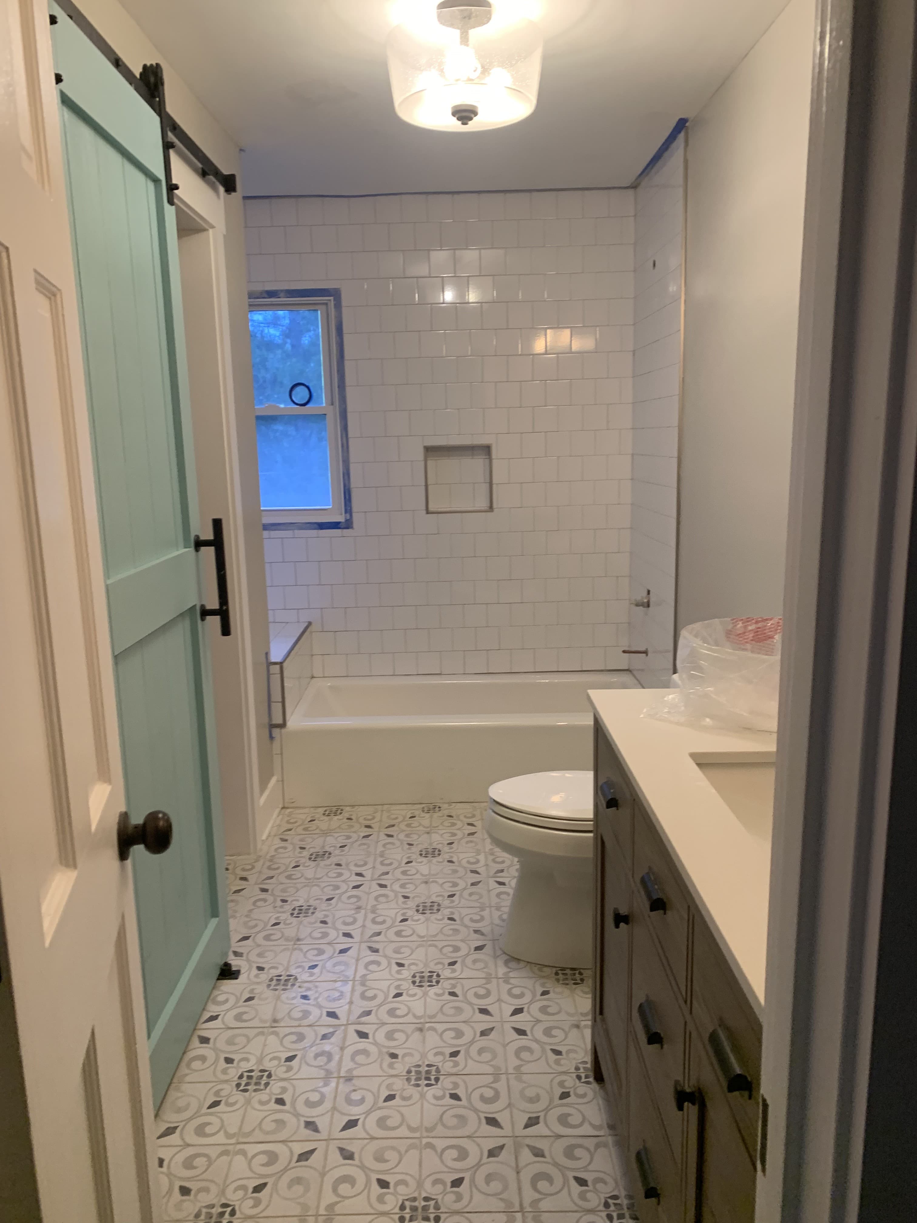Farmhouse-style bathroom with patterned tile floor and barn door entry
