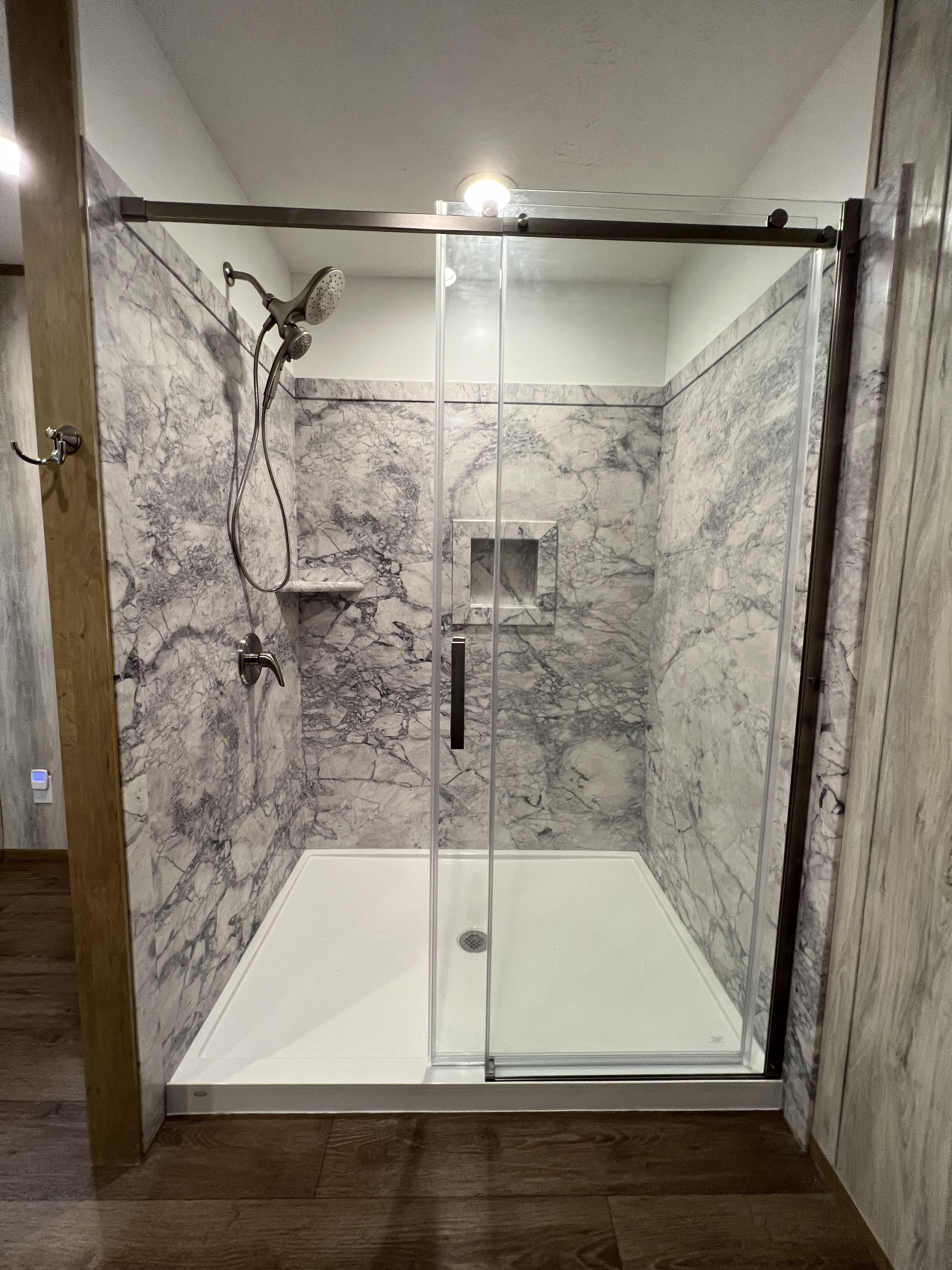 Gray marble walk-in shower with glass sliding doors and modern fixtures