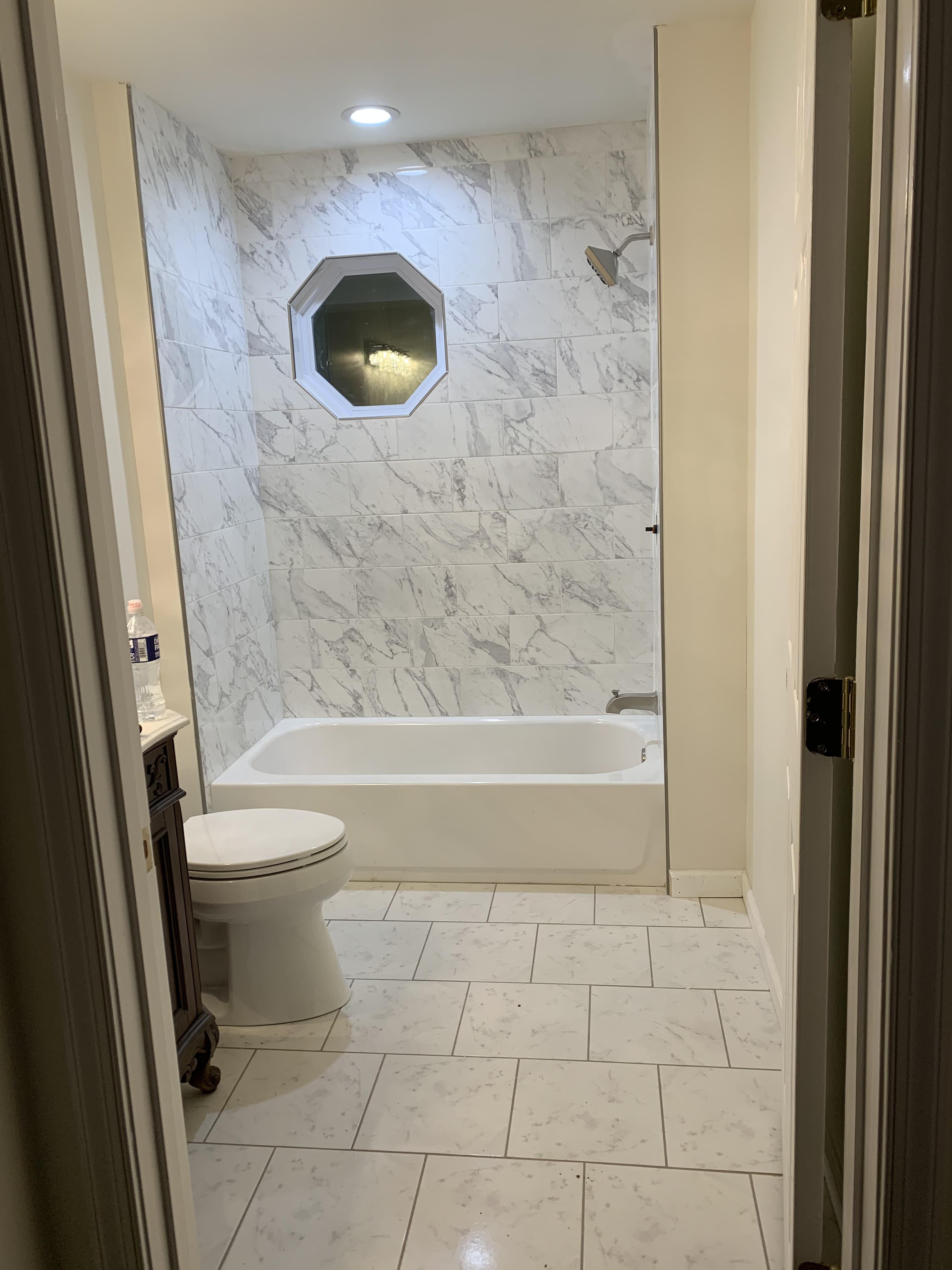 Marble tile bathroom with tub surround and octagonal window detail