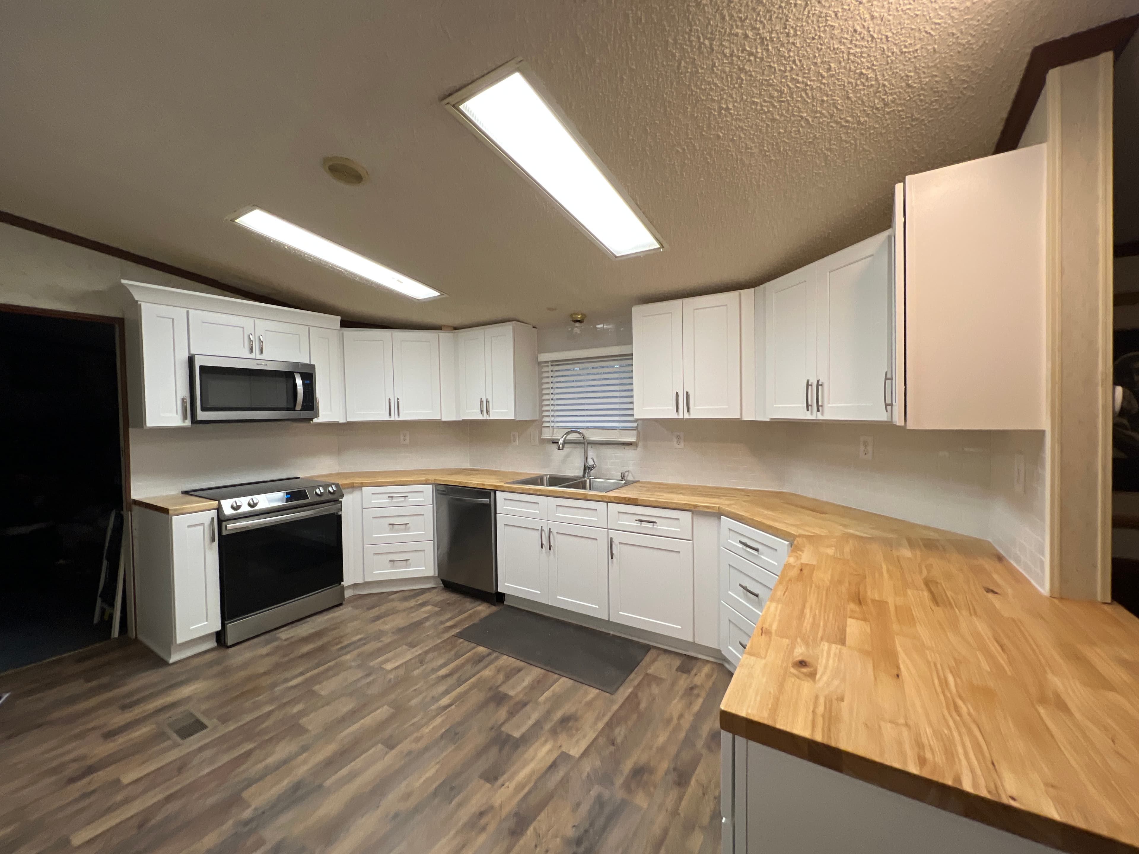 White Shaker cabinet kitchen with wood flooring and modern lighting