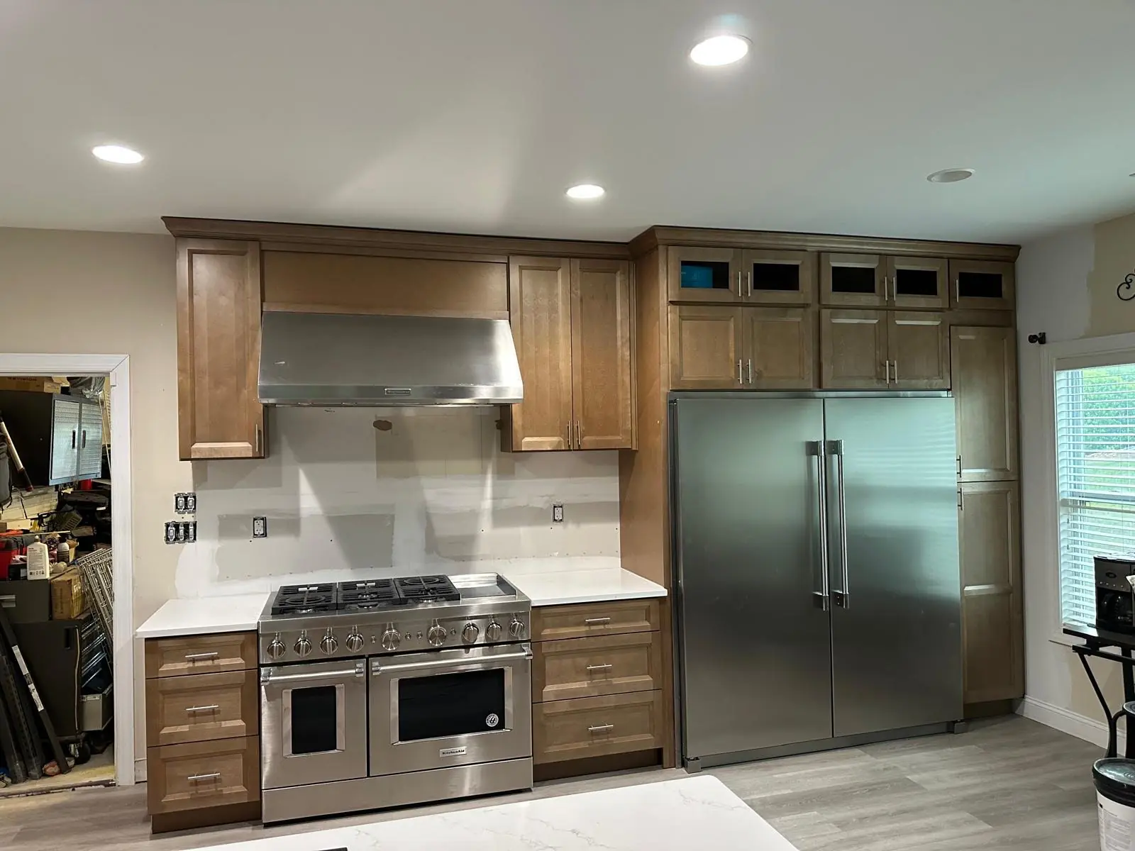 Kitchen renovation in progress with wood cabinets, white countertops, a stainless steel range and refrigerator, and an unfinished backsplash