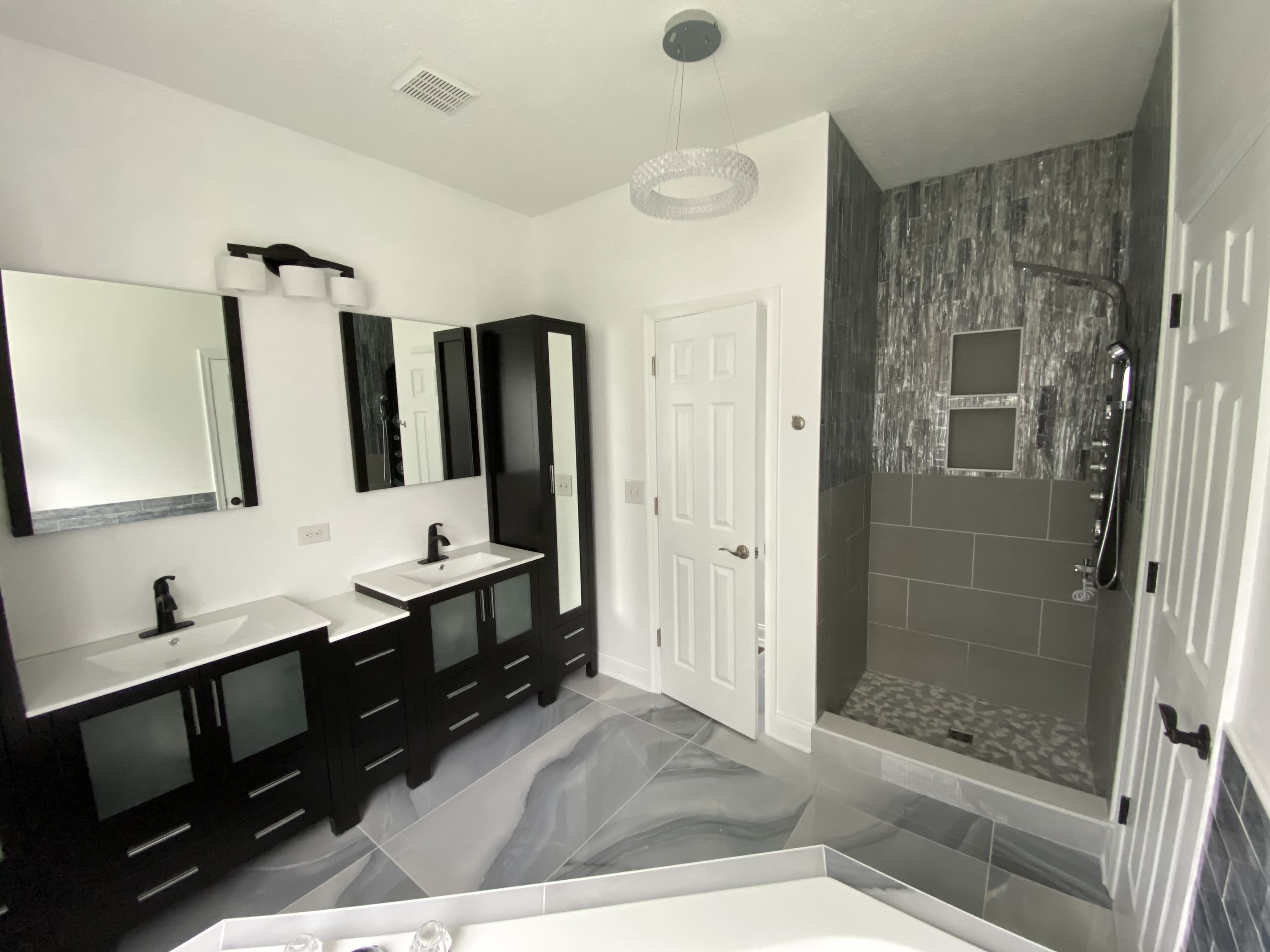 Double vanity bathroom with a custom tiled walk-in shower and gray marble flooring